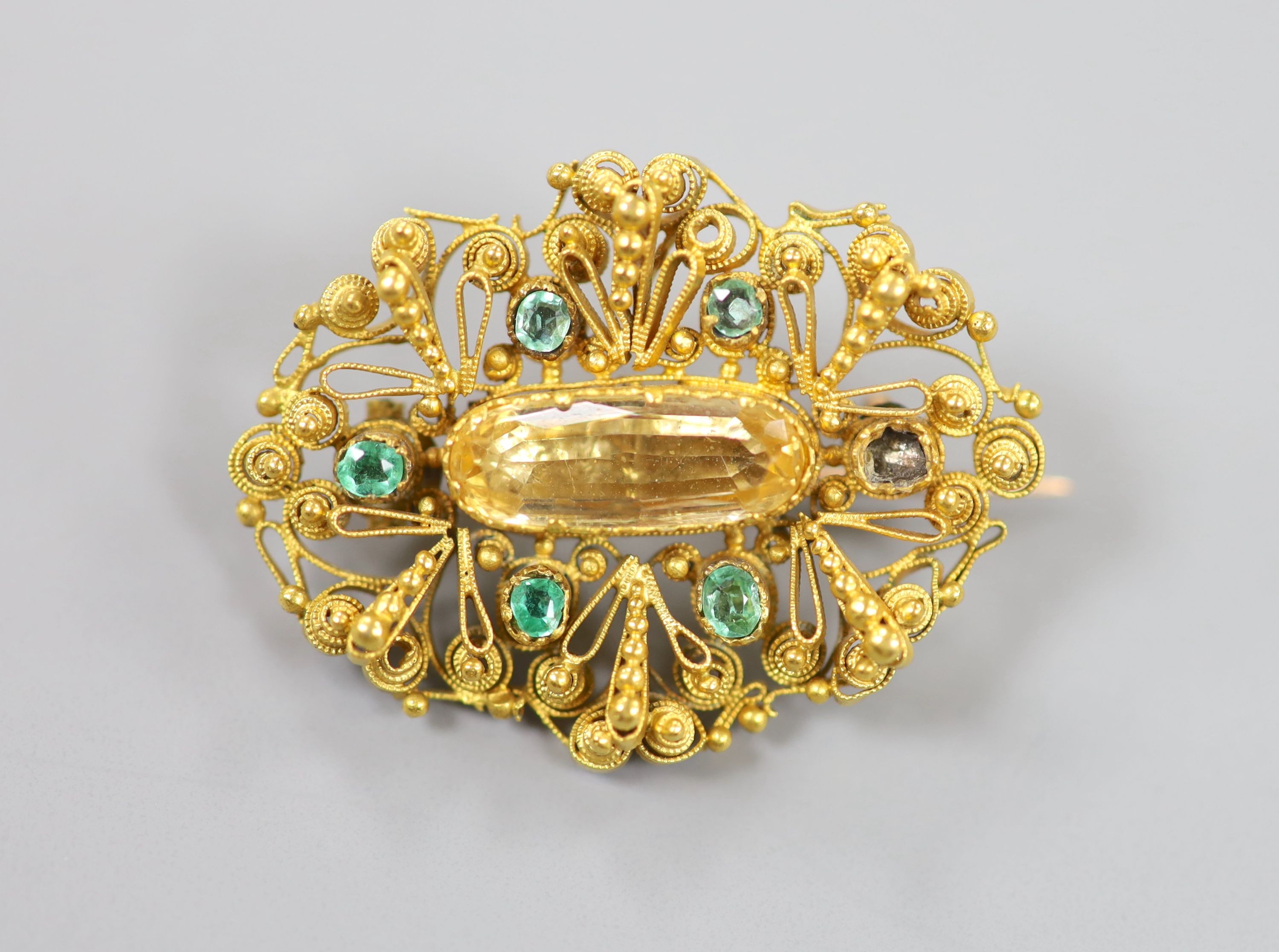 An early 20th century filigree yellow meta, emerald and citrine set oval brooch (emerald missing), 35mm, gross weight 8.4 grams.